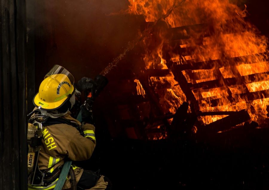 A firefighter with a hose, fighting a fire.