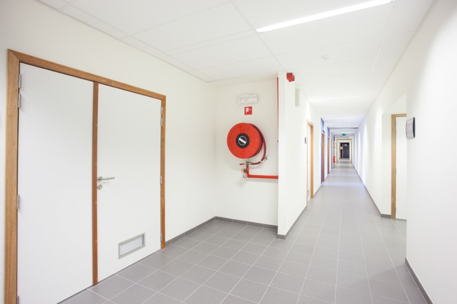 A fire hose mounted on a wall in a hallway.