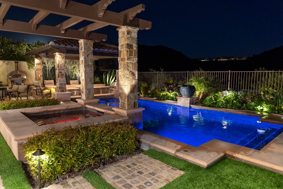 Image is of a backyard pool at a modern smart home.