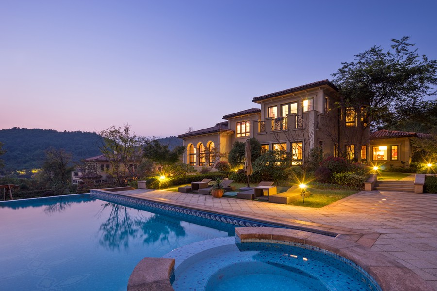 A large well-lit home with a pool and outdoor lighting.