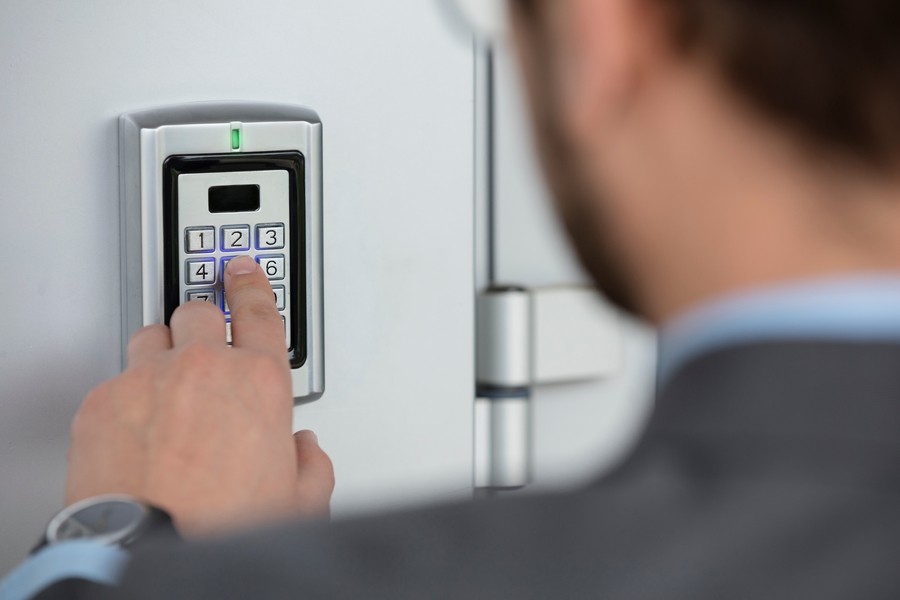 A close-up of a man entering a code on an access control system keypad to enter a building in Springfield, MO. 