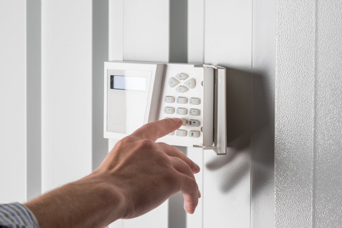 Image is of a person pushing buttons on a security alarm keypad.