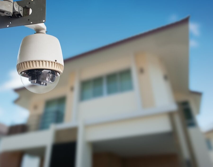 A smart surveillance camera in focus with a home in the background.